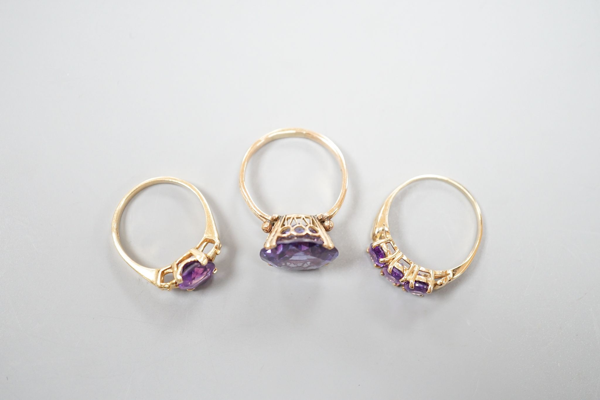 Two modern 14k yellow metal and gem set rings, including amethyst, size N, gross weight 7.4 grams and a similar 10k and three stone amethyst ring, size Q/R, gross 2.3 grams.